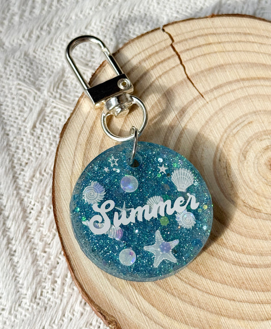 Round blue resin pet tag with seashell design, personalized with pet's name and phone number for dogs and cats