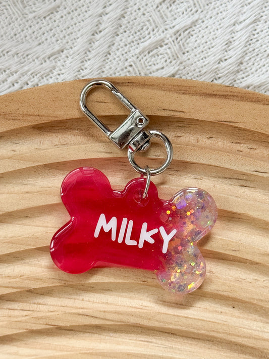 Bone-shaped red resin pet tag with iridescent sparkle, personalized with pet's name and phone number for dogs and cats